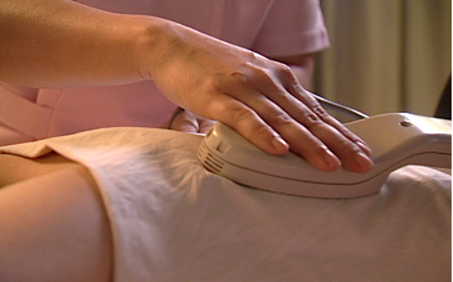 琉球温熱療法の施術風景。女性の腰を集中的に温めている様子